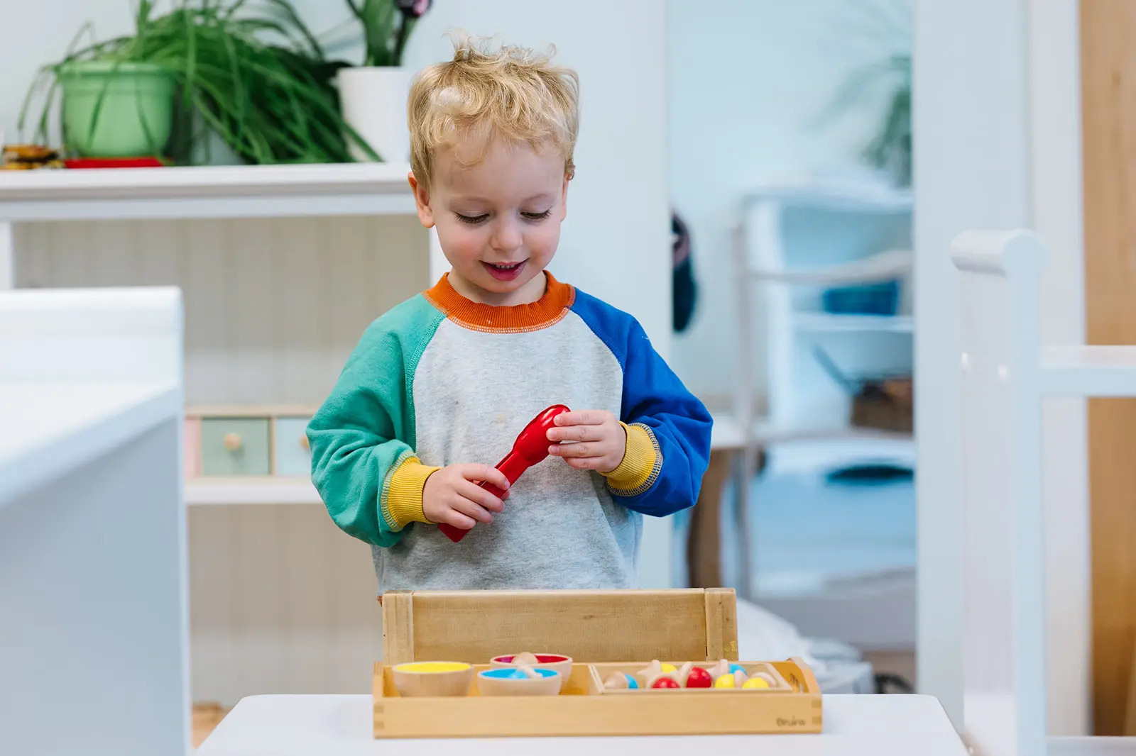 Young child playing with colorful wooden blocks at a table.