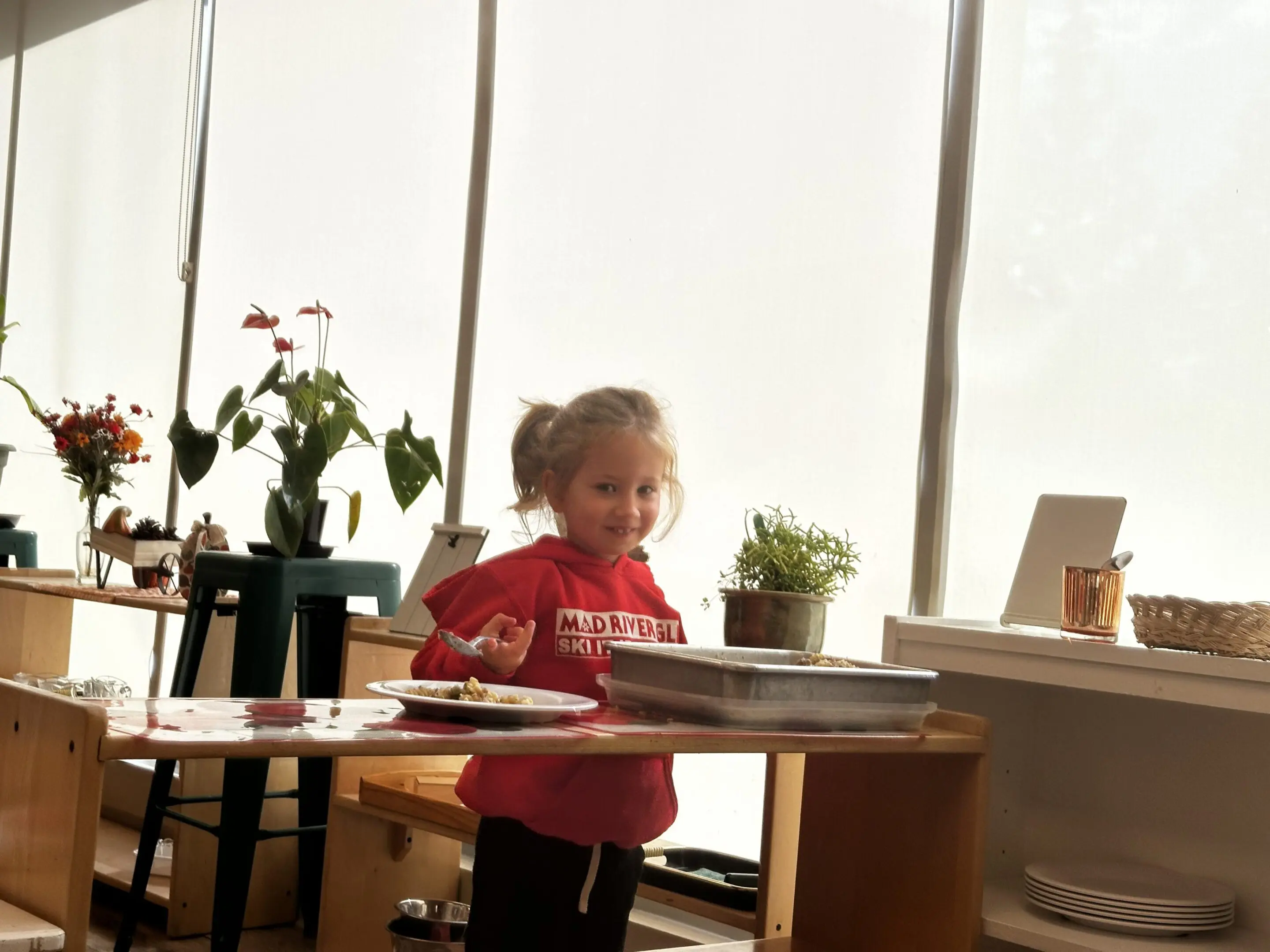 A young child playing with toys on a table near a bright window.