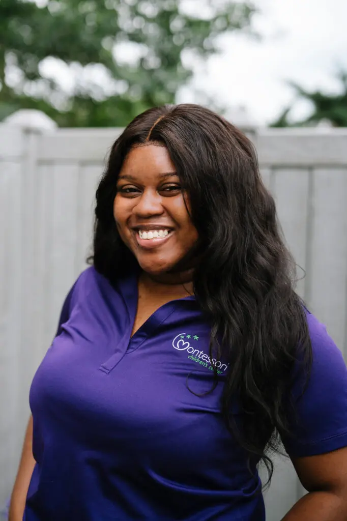 Smiling woman in purple shirt outdoors.