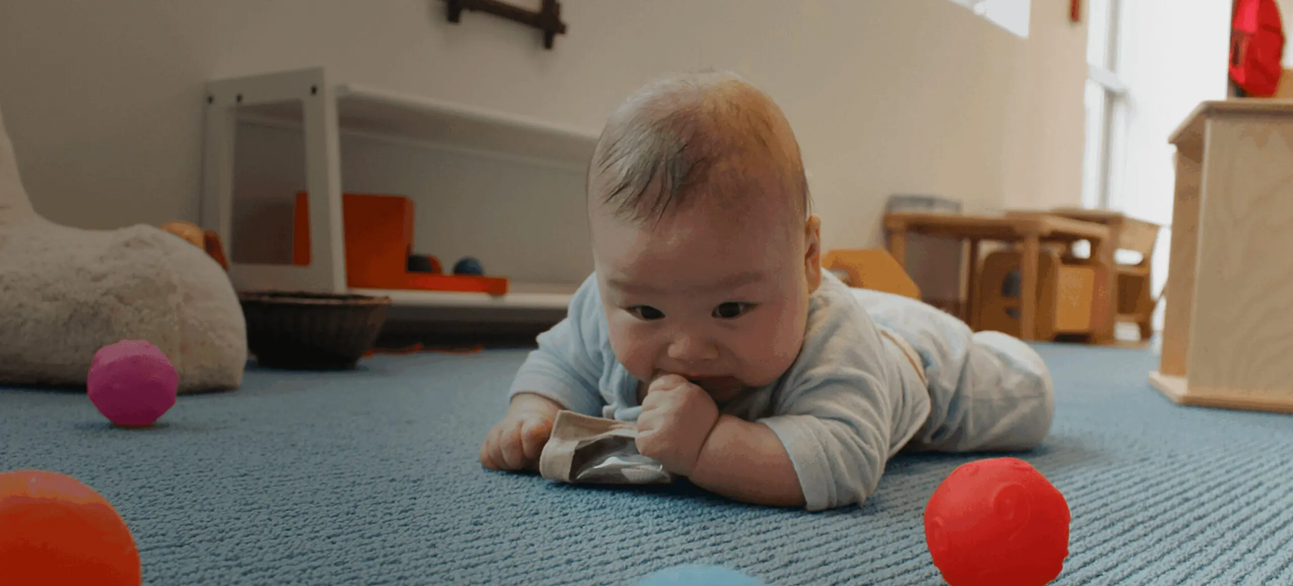 Baby playing with toys on carpeted floor.