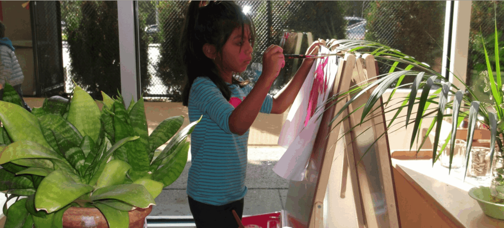 Child painting at an indoor easel station.