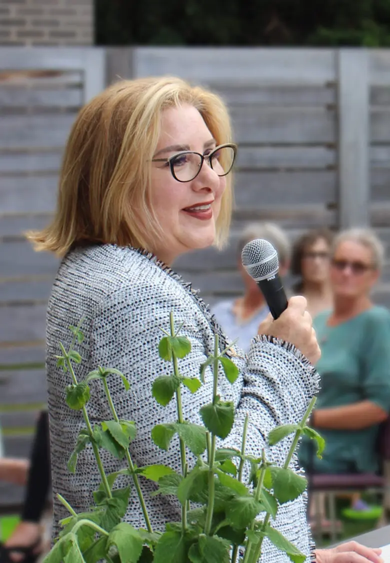 Woman speaking confidently with a microphone outdoors.