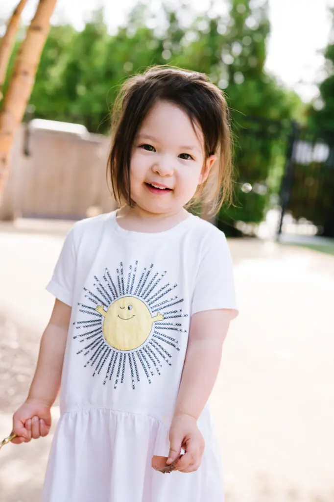 Smiling child wearing a sun-themed shirt.
