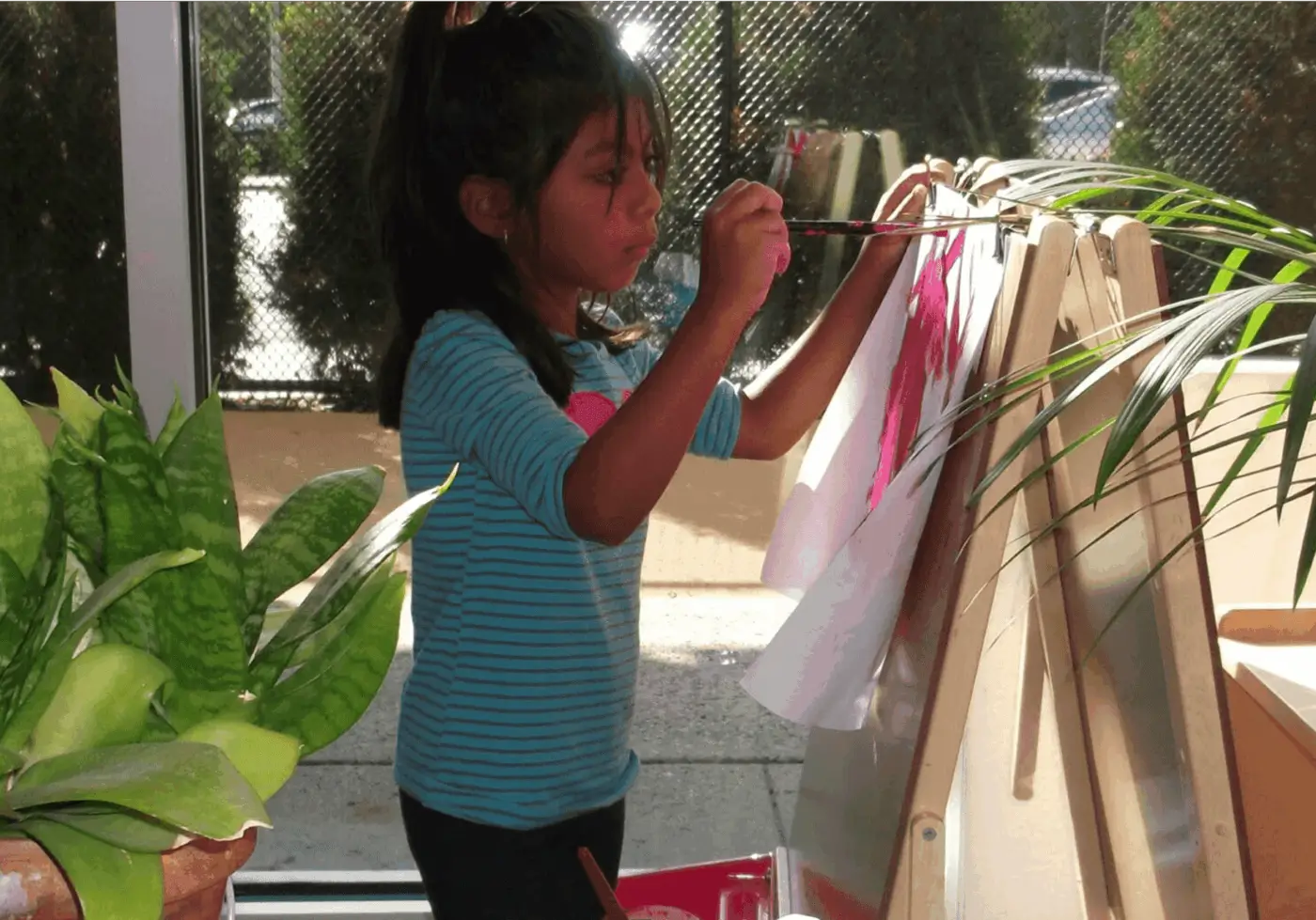 Young girl painting at easel by window