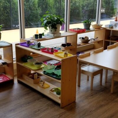 Classroom with shelves and small tables.