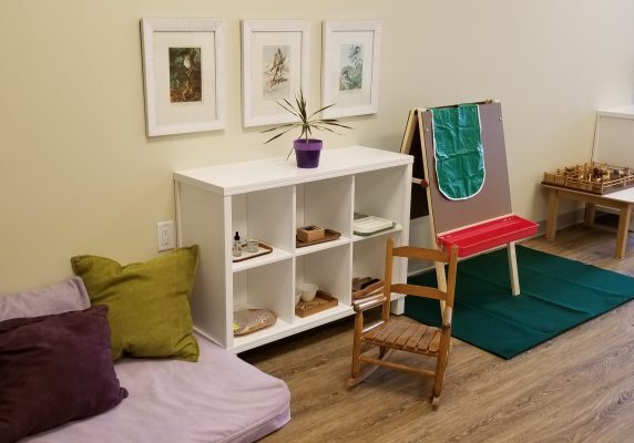 Montessori classroom with shelves and easel.